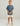 Boy wearing slate blue short-sleeve tee with small logo on chest, paired with cream shorts and tan boat shoes.