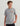 Child wearing gray short-sleeve t-shirt with HUK logo and graphic design on chest, paired with black shorts.
