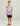 Child wearing gray Huk performance crew with orange logo and text, black shorts, and tan sandals.