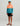 Boy wearing coral and teal colorblock hoodie with "HUK" branding, black shorts, and turquoise cap.