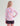 Girl wearing pink, coral, and blue camo-patterned long-sleeve hoodie with circular back logo and black shorts.
