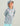 Child wearing light blue and mauve camo hoodie with white logo and matching cap.