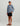 Boy wearing gray and blue camo long-sleeve crew shirt, black shorts, white and blue cap, and black sandals.