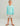 Child wearing turquoise long-sleeve crew neck shirt and patterned shorts with brown sandals.