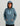 Child wearing slate blue Huk hoodie with large logo print, hood up, hands in kangaroo pocket with orange lining.