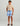 Boy wearing blue and white patterned volley swim shorts with drawstring waist and front pockets.